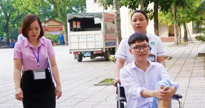 Nhân viên y tế đẩy xe lăn đưa nam sinh đến phòng thi
