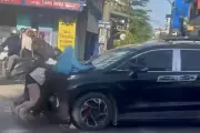 Ba phụ nữ bám capo ô tô đang chạy trên quốc lộ 1A ở Hà Nội