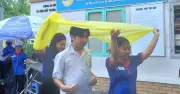Tình nguyện viên che mưa cho thí sinh tại điểm thi Gò Vấp